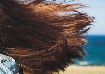 red hair blowing in the wind beach background